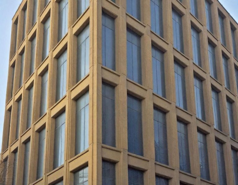 Natursteinsanierung Moderne Architektur mit mehreren Fenstern und einem klaren, geometrischen Design. Fassade aus Sandstein.